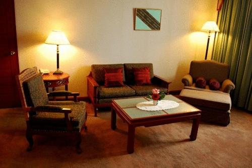 a living room with couches and a coffee table at Charoen Thani Hotel, Khon Kaen in Khon Kaen