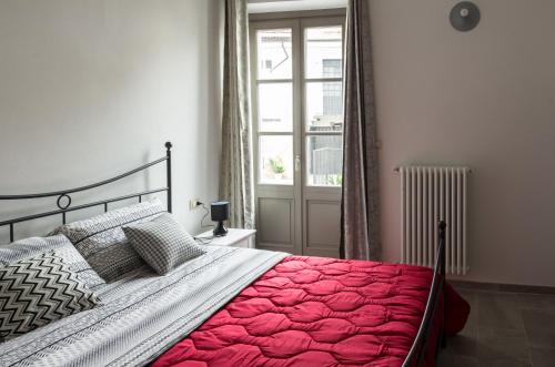 - une chambre avec un lit doté d'une couverture rouge et d'une fenêtre dans l'établissement La Tintoria Suites, à Asti