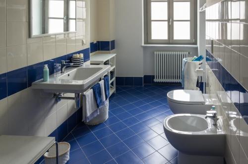 baño de azulejos azules con 2 lavabos y aseo en La Tintoria Suites en Asti