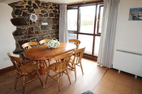 a dining room with a wooden table and chairs at Houndapitt Cottages in Bude