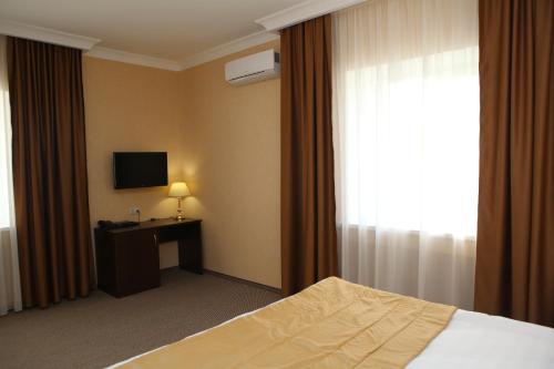 une chambre d'hôtel avec un lit et une télévision dans l'établissement Hotel Aner, à Astana