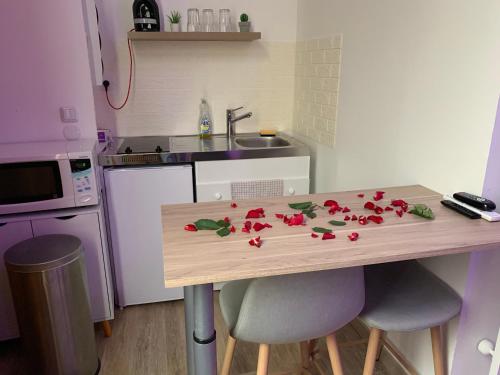 a kitchen with a table with red flowers on it at Appartement Spa - NAHLEO Scandinave in Dole
