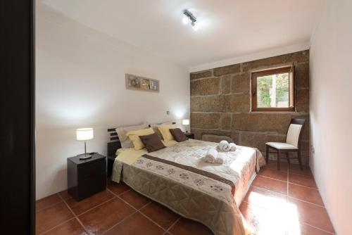een slaapkamer met een bed en een bakstenen muur bij LovelyStay - Casa Guimas in Penafiel