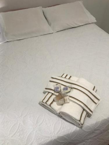 a white bed with a tray of towels on it at Taty Flats in Rio das Ostras