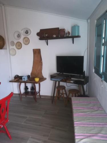 a living room with a table and a desk with a television at Monchique Typical House in Monchique