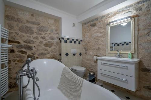 bagno con vasca bianca e parete in pietra di Apartments INN Baska Voda a Baška Voda