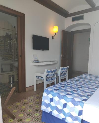 a bedroom with a bed and two chairs and a tv at Taverna Del Capitano in Massa Lubrense