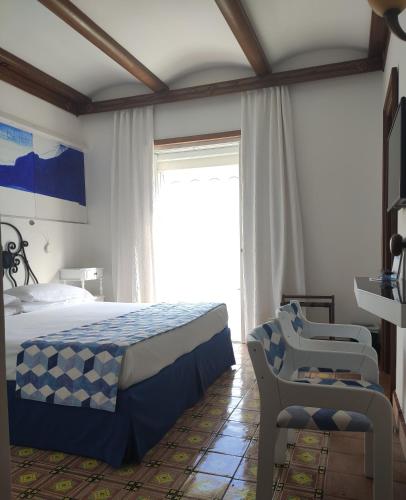 a bedroom with a bed and a chair and a window at Taverna Del Capitano in Massa Lubrense