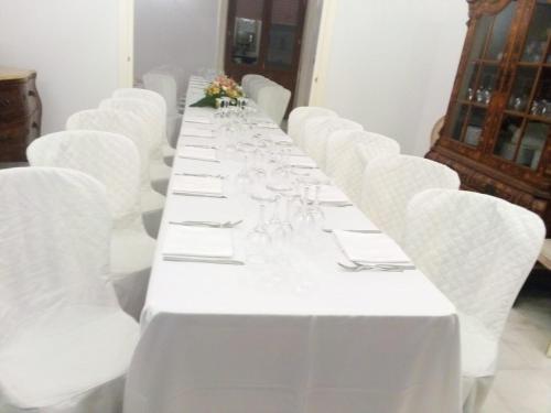 una mesa larga con sillas blancas y copas de vino en Spa sul tempio d'apollo en Siracusa