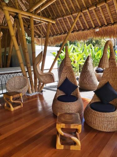 a room with wicker chairs and chairs on a wooden floor at Keliki Luxury Lodge in Ubud