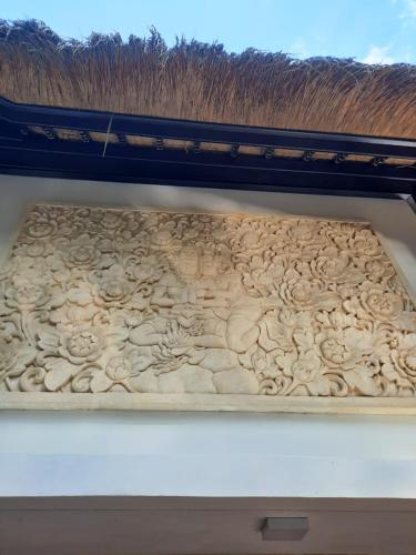 a wooden wall with a carving of flowers on it at Keliki Luxury Lodge in Ubud