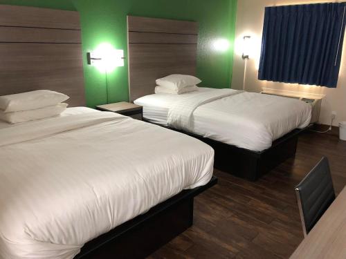 duas camas num quarto de hotel com paredes verdes em Travelers Inn and Suites Wharton em Wharton