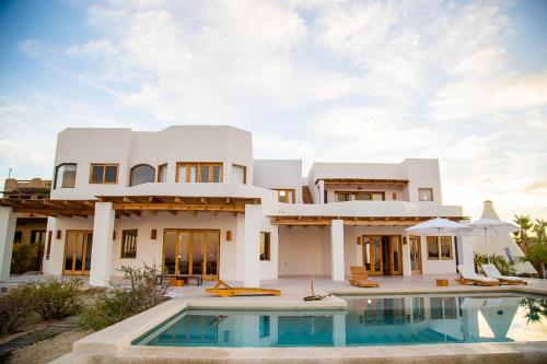 a large white house with a swimming pool in front of it at Tribu Todos Santos in Todos Santos