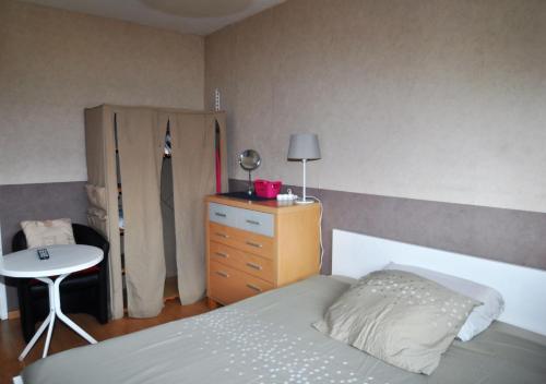 a bedroom with a bed and a dresser and a table at appartement 3 chambres, idéal pour déplacement in Échirolles