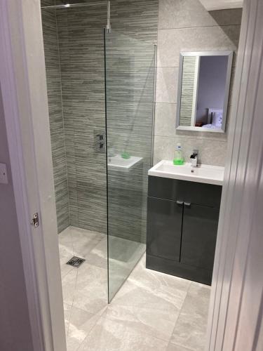 a bathroom with a glass shower and a sink at White House Cottages in Durham