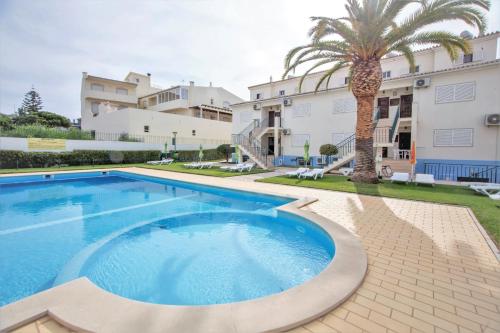 a swimming pool in front of a building with a palm tree at Atlantico Sul in Quarteira