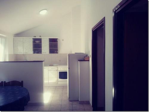 a kitchen with white cabinets and a refrigerator at Apartment Lopar 27 in Lopar