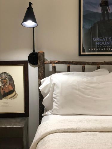 - une chambre avec un lit doté de draps blancs et d'une lampe dans l'établissement Highlander Mountain House, à Highlands
