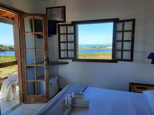 a room with a bed and two windows and the ocean at Pousada Icthus in Cabo Frio
