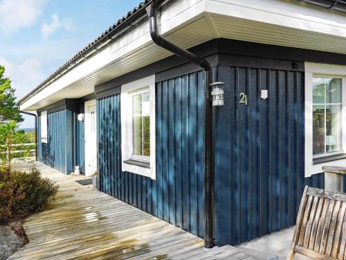 Casa con revestimiento azul y terraza de madera en 8 person holiday home in Hen n en Henån