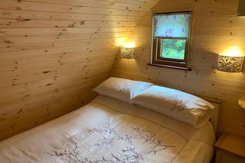 Bett in einem Blockhaus mit zwei eingeschalteten Lampen in der Unterkunft Birdsong Lodge in Woolacombe