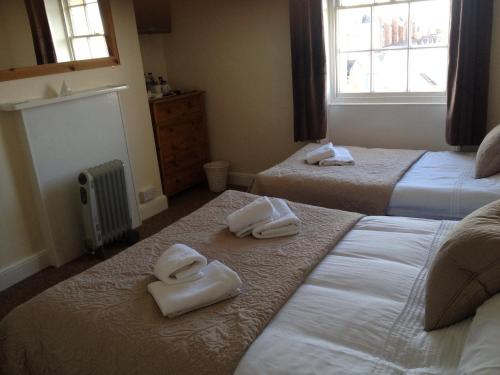 a hotel room with two beds with towels on them at Arcadia Guest House in Weymouth