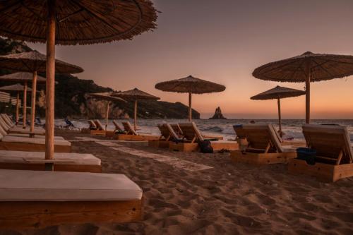 a group of chairs and umbrellas on a beach at Romantic Palace Beach Apartments in Agios Gordios