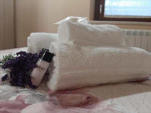 a pile of towels on a table with a bottle of soap and flowers at Affittacamere Il Tiro a Segno in Norcia