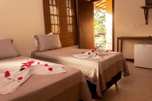 a bedroom with two beds with flowers on them at Pousada Lagoa Da Pedra in Imbassai