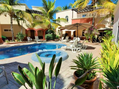 un patio con piscina, sillas y palmeras en Coco Cabañas and Casitas Vacation Rentals, en Loreto