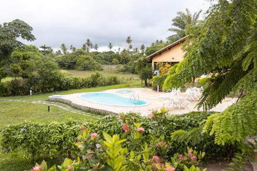 a yard with a swimming pool and a house at Pousada Lagoa Da Pedra in Imbassai