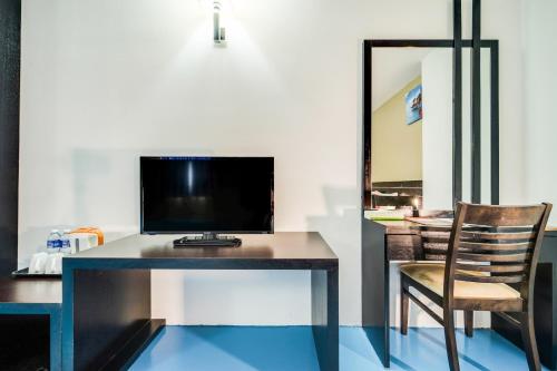 a desk with a television and a chair in a room at Kuala Melaka Inn in Pantai Cenang