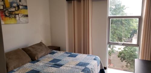 ein Schlafzimmer mit einem Bett und einem großen Fenster in der Unterkunft Departamento Equipetrol Ejecutivo Familiar in Santa Cruz de la Sierra