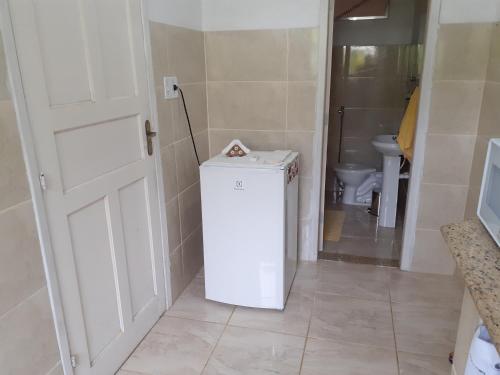 a small white refrigerator in a bathroom with a toilet at Casa Chalé em Penedo in Penedo