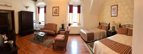 a bedroom with two beds and a couch and chairs at Hotel Casa Divina Oaxaca in Oaxaca City