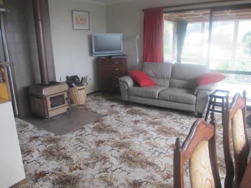 a living room with a couch and a television at Catlins Lake Sanctuary in Owaka