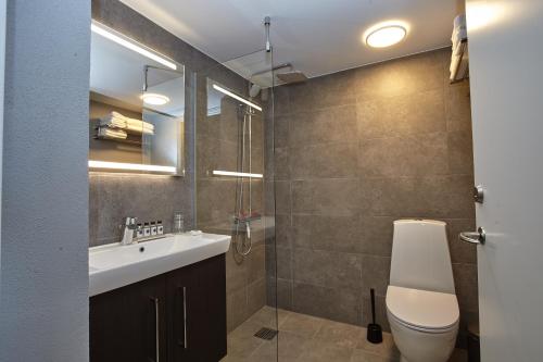 a bathroom with a sink, toilet and shower at Hotel Nor - Badehotellet in Fjerritslev
