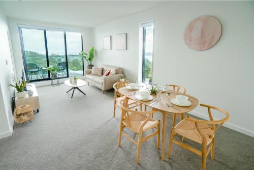 - un salon avec une table, des chaises et un canapé dans l'établissement CHELSEABAY Modern Apartments, à Auckland