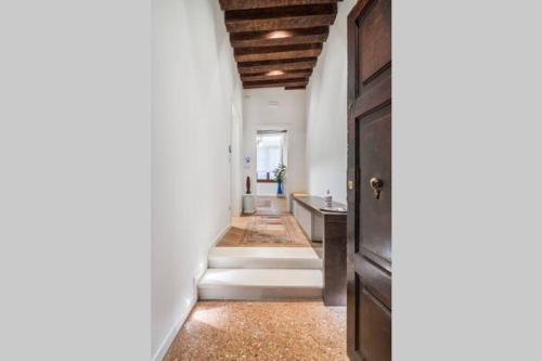 a hallway with white walls and a wooden door at Appartamento Cassiano Rialto in Venice