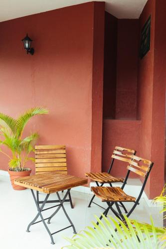 two chairs and a wooden bench next to a red wall at Hotel Arcadia in Panaji