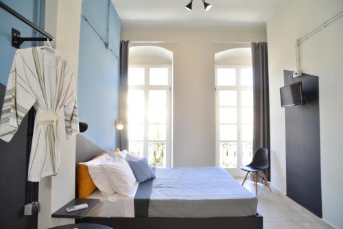 a bedroom with a bed and two windows at Habit in Ermoupoli