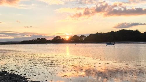 a sunset over a body of water with a boat at Turlin Valley in Poole