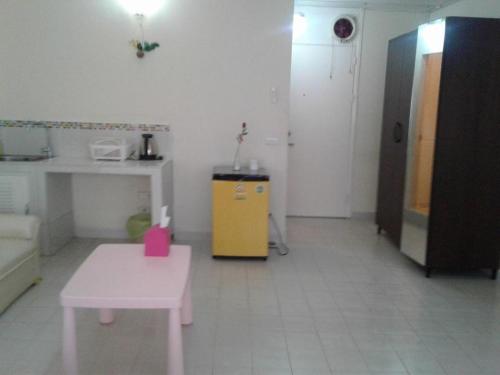Thung Si KanにあるAsia Don Mueang Bangkok Condominiumのピンクのテーブルと黄色のキャビネットが備わる部屋