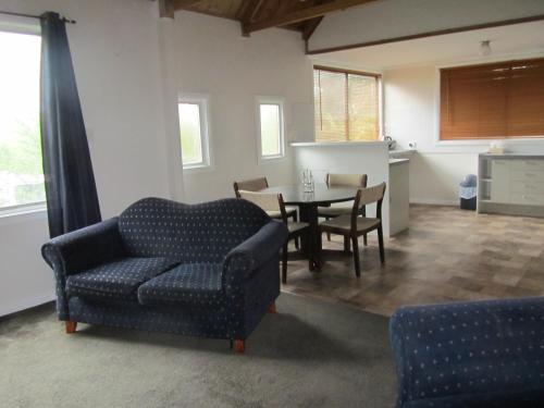un soggiorno con divano e tavolo di Acacia Cottage a Tumbarumba