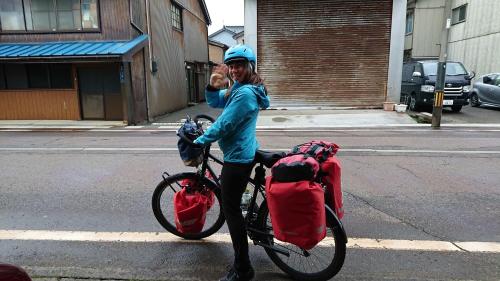 a woman standing next to a bike on a street at Live Cafe Hisui no Umi in Itoigawa