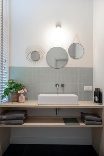 a bathroom with a sink and mirrors on the wall at Boutique Hotel - de Stadsherberg Alphen in Alphen aan den Rijn