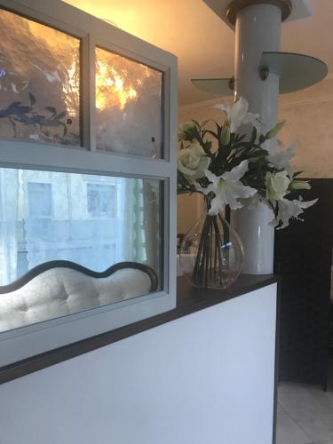 a vase of flowers on a counter with a window at Hotel Martin in Volpiano