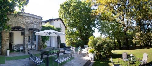a patio with tables and chairs and an umbrella at "La Selvetta" bed and breakfast in Buguggiate