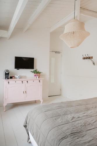 a white bedroom with a bed and a tv at Boutique Hotel - de Stadsherberg Alphen in Alphen aan den Rijn