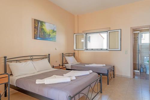 a bedroom with two beds and a window at Akrogiali Studios in Poros